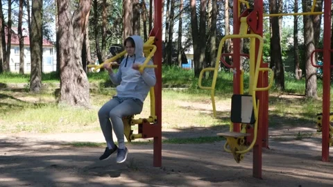 Single young man doing exercises at street gym apparatus in park, street workout Stock Footage 153950230