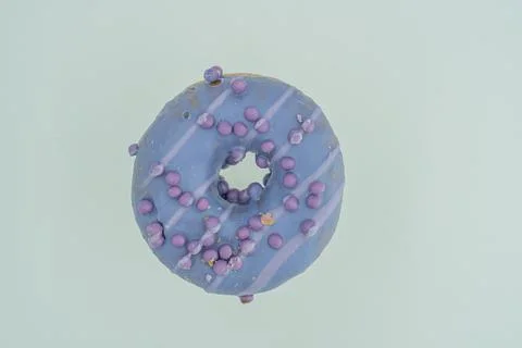 A singular, purple-glazed doughnut with tiny circular decorations is featured Foto stock