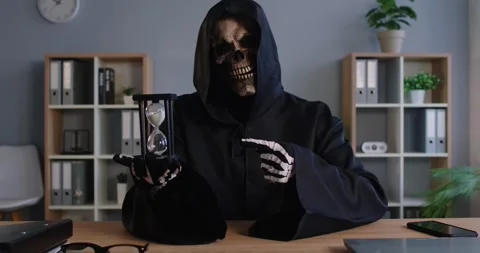 Sinister grim reaper of death in dark cloak pointing at hourglass while Stock Footage 329287692