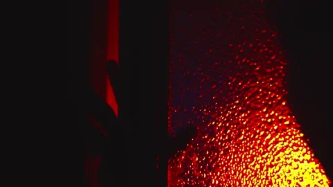 Sinister scary silhouette crawls, opens glass door under red light Stock Footage 253802736