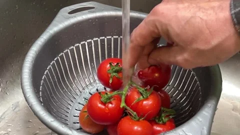 A sink with a silver colander filled with tomatoes and water Stock Footage 319955879