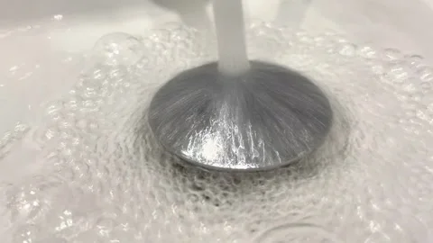 A sink with a silver faucet and a round metal cover Stock Footage 314896135