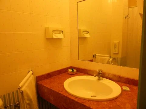 Sink under yellow light. Reflection of the bathroom in the mirror Stock Photos