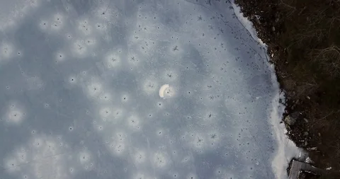 Sinking down toward a frozen winter lake with a green bouy in the ice Stock Footage 122400160