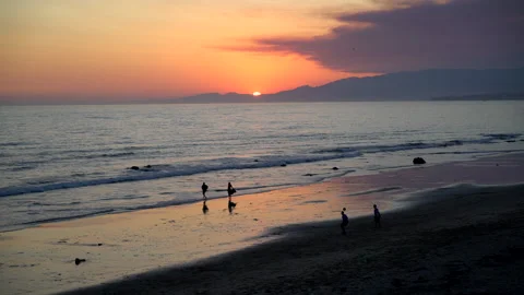 Sinking Sun with Backlight Silhouettes and Surfer Mirrored on the Beach Stock Footage 197786169