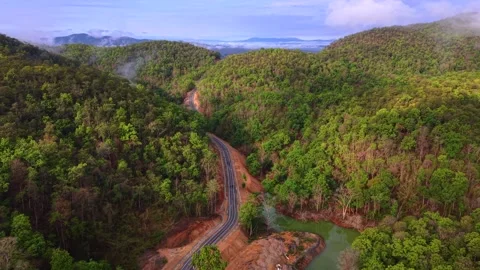 Sinuous mountain pass through lush tropical highlands with morning mist Stock Footage 334654963
