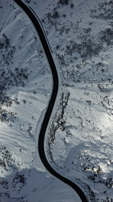 Sinuous Road Weaving Through Snowy Hillside from Above Vidéo 334772310