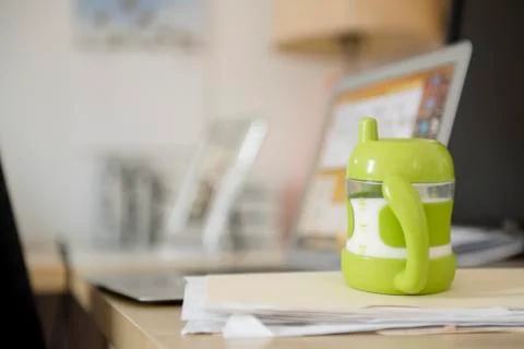 Sippy cup on file folder near laptop Stock Photos
