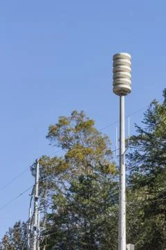 Siren tower rising between trees, against a blue sky, space for text Stock Photos