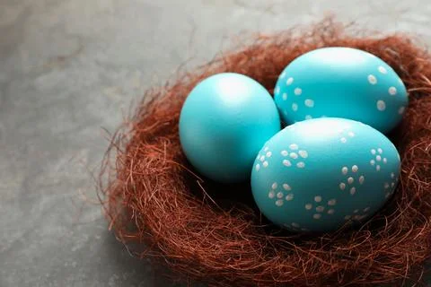 Sisal nest with painted Easter eggs on color background, closeup. Space for t Stock Photos