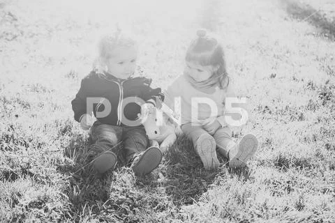 Sister and brother play with toy horse on sunny day Stock Photos
