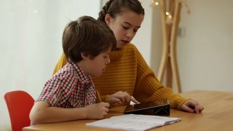 Sister Helping Younger Brother To Do Homework With Tablet. Stock Footage 101199191