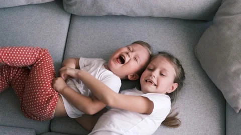 Sister tickles brother while lying on the couch. Stock Footage 178334555
