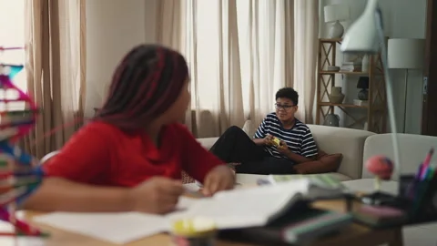 Sister trying to study while her brother loudly plays video games nearby Stock Footage 334947666