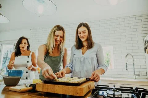 Sisters baking scones together while mother looks on Stock Photos