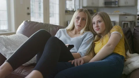 Sisters cuddling on sofa and watching te... | Stock Video | Pond5