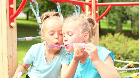 Sisters delight in bubble fun during sunny afternoon at the park Vídeos de archivo 296335627