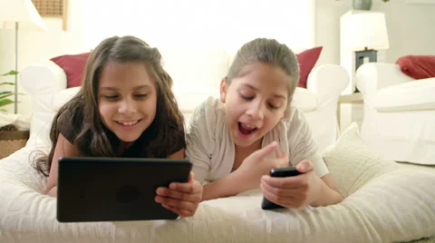 Sisters lie on the ground using different tablet and another a cell phone Video stock 34015401