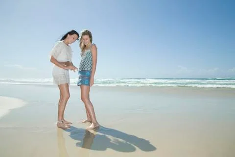 Sisters looking at shell on beach Stock Photos