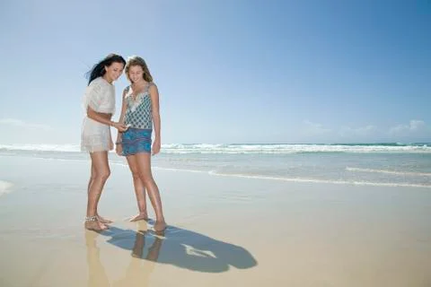 Sisters looking at shell on beach Stock Photos