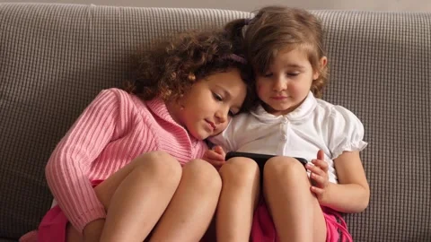 Sisters lovingly watching a video on the couch together Stock Footage 308019281