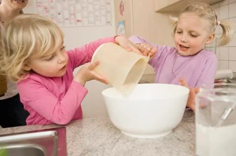 Sisters making cake in kitchen Foto stock