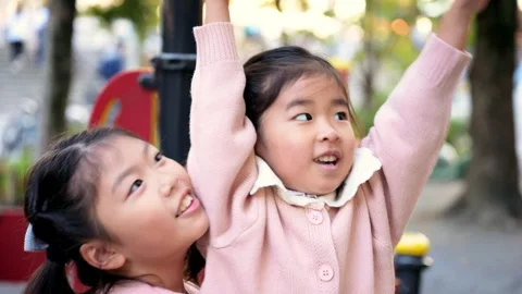 Sisters playing outside in a park, at a playground in Tokyo Japan Stock Footage 295819401