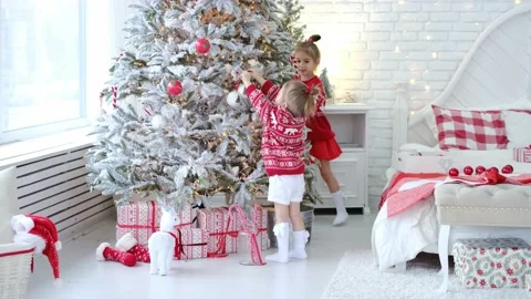 Sisters in red sweaters decorate an artificial Christmas tree Stock Footage 165805270