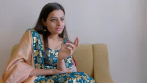 Sisters share and chat as they seated on a sofa in a nicely decorated interior o Stock Footage 101273076