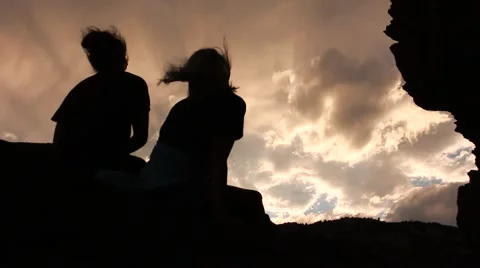 Sisters sitting on a boulder looking up to the sky Vídeos de archivo 53771656