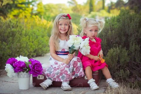 Sisters two both blond with deep ice blue eyes wearing colourful dresses posing Stock Photos