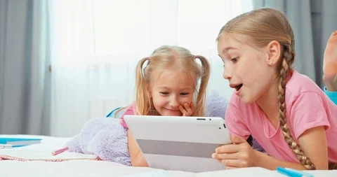 Sisters using tablet pc, lying on the bed Stock Footage 95645241