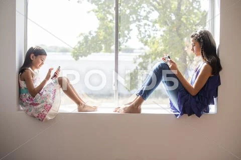 Sisters Using Technology In Window