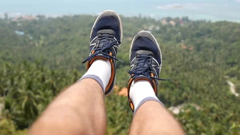 Sit high on the top of the mountain, dangling your legs down over the edge view Stock Footage 91248229