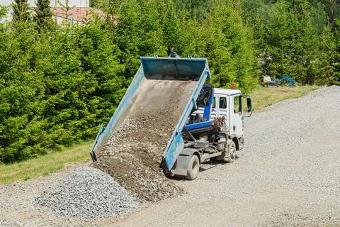 On the site of a construction project, a dump truck is dumping gravel. Stock Photos