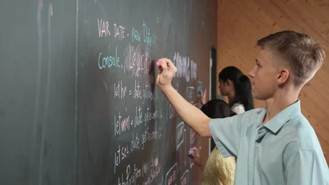 Site view of boy writing code on blackboard with diverse friend. Edification Stock Footage 276147462