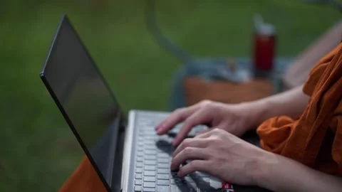 Sitting and typing at the computer in the park Stock Footage 280499403