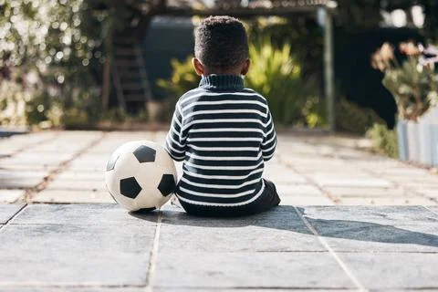 Sitting, back and a child in yard with a ball for soccer, playing and childhood Stock Photos