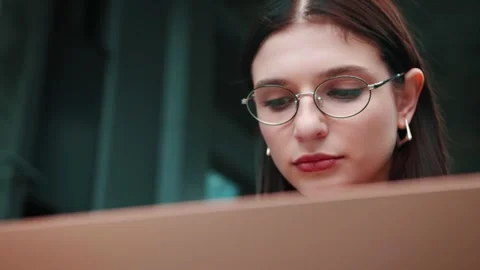 Sitting on the bench and using laptop. Woman in formal clothes is outdoors near Video stock 241606433