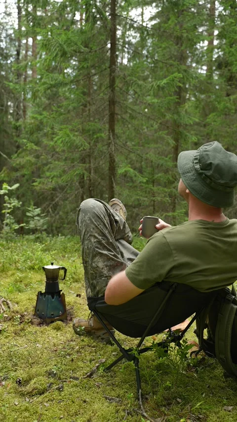 Sitting in a camp chair and drinking coffee in a pine forest Stock Footage 340653933