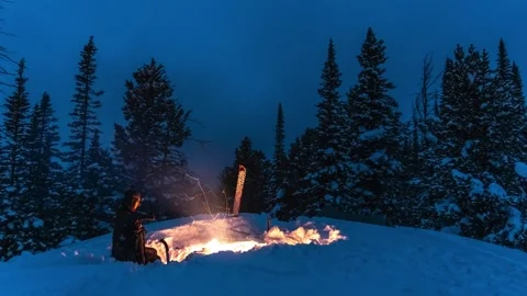 Sitting by campfire in the winter in deep snow at night timelapse Stock Footage 310539471