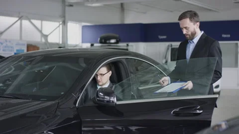 Sitting in a car customer is reading the contract for the purchase of the car in Stock Footage 137388556