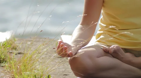 Sitting in the Cross-Legged Lotus Position on a sunny and breezy day by water Stock Footage 59742342
