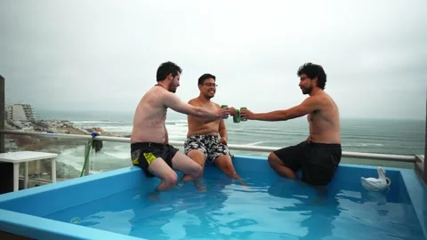 Sitting at the edge of a pool overlooking the beach with friends opening, Stock Footage 181902086