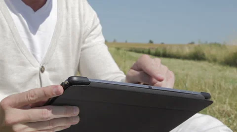 Sitting at a field surfing on a tablet Stock Footage 52646473