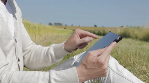 Sitting at a field surfing on a tablet Stock Footage 52646650