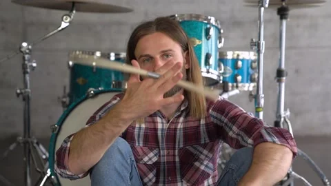 Sitting in front of the drums Look directly onto camera. spinning a drum stick Stock Footage 155553938