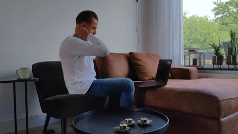 Sitting frustrated man is working from home and is typing on his laptop Stock Footage 211887048