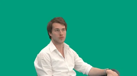 Sitting guy gets a call on his mobile phone - green screen - pre keyed - MINT.GS Video stock 8647126