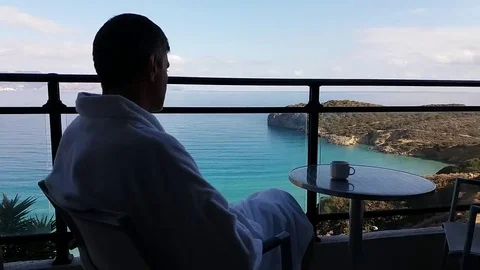 Sitting with his back to the man on the balcony with sea views Stock Footage 69221469